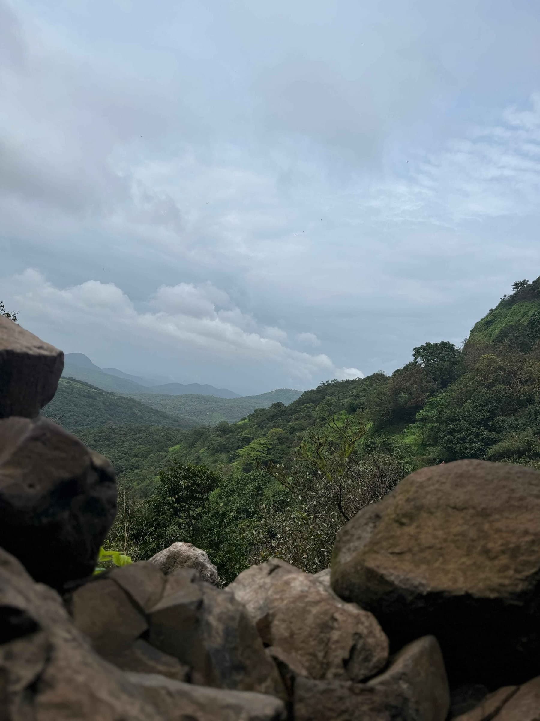 Clouds over a green valley, seen past boulders