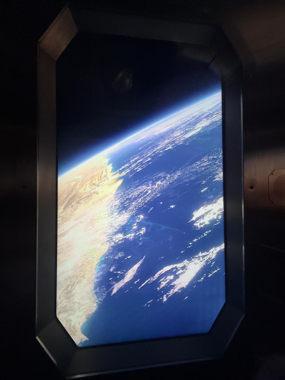 Earth seen from orbit through a spacecraft-style window