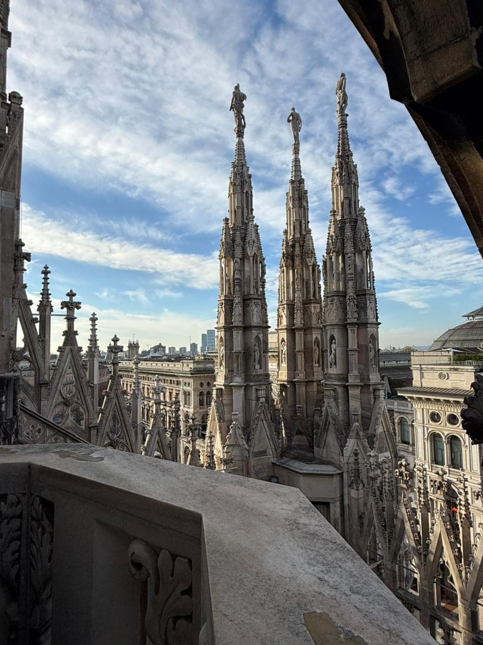 Spires of Milan Cathedral against a blue sky, seen from its roof